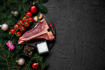 Christmas raw T-bone steak on a background with a fir tree and Christmas toys with copy space for your text