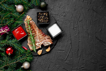 Christmas T-bone steak cooked on the grill against the backdrop of a Christmas tree and Christmas decorations with copy space for your text