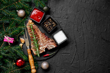Christmas T-bone steak cooked on the grill against the backdrop of a Christmas tree and Christmas decorationswith copy space for your text 
