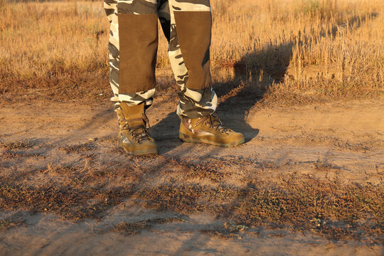 A tourist in trekking boots walks along a field road