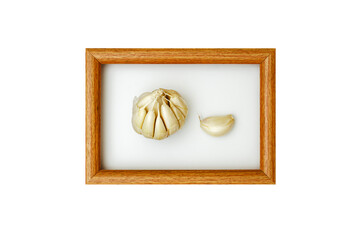 Garlic bulb and a single clove in a wooden frame