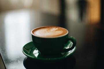 A green cup of hot coffee is placed on the table.