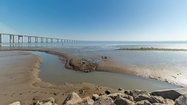 Panorama showing motion from the low to high tide next to Vasco da Gama Bridge in Parque das Nacoes timelapse in Lisbon, Portugal. Level of water is rising up. Waterfront in Park of Nations district