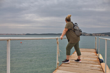 Obraz premium Woman on the jetty looks into the distance