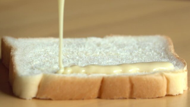 Pouring condensed milk on a bread