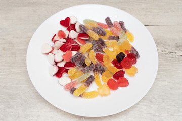 Various chewable candies and marmalade worms in plate