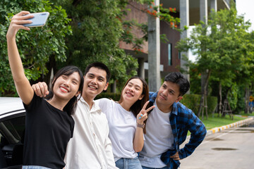 Group of happy young Asian students selfies and videos with smartphones together for vlog and social media on summer vacation. Concept of tourism and travel and road trip, friendship lifestyle.