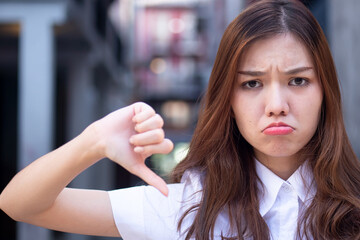 Upset Chinese asian woman office worker pointing rejecting thumb down hand gesture