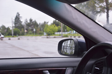 Automobile parts are black in color, such as window, steering wheel, side outside mirror. View from...