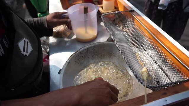 Seller of egg roll snacks (traditional Indonesian snack) pouring batter into a frying pan close-up