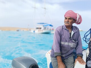 The photo features an old sailor with a white mustache who is a retired soldier in the navy wearing a Bedouin scarf on his head