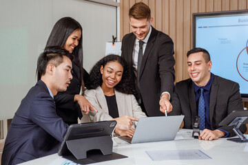 Team of business men and women looking at computers and celebrating successful business in conference room