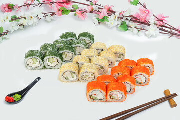 sushi set, a lot of rolls, sakura branch and chopsticks, on a white isolated background © Kurganskiy