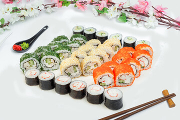 sushi set, a lot of rolls, sakura branch and chopsticks, on a white isolated background © Kurganskiy