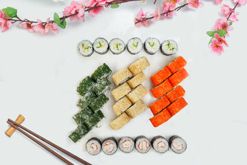 sushi set, a lot of rolls, sakura branch and chopsticks, on a white isolated background © Kurganskiy