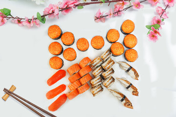 sushi set, a lot of rolls, sakura branch and chopsticks, on a white isolated background © Kurganskiy