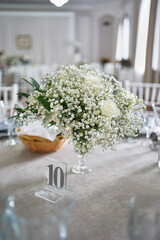 Serving the festive table with dishes, glasses, numbers and a bouquet of flowers. Restaurant interior.