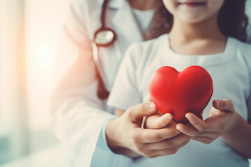 Child and adult holding a red heart with stethoscope - obrazy, fototapety, plakaty