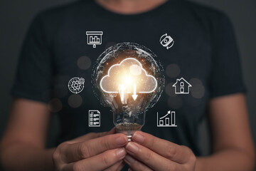 A light bulb that shines in the hand of a businessman. One idea for transmitting business information using cloud technology. Ideas from searching for economic data for marketing. - obrazy, fototapety, plakaty