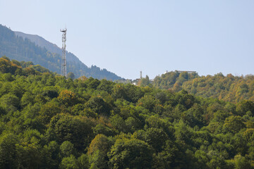 Metal structure, communication tower in a mountainous area, against the background of high mountain peaks. Russia, Krasnaya Polyana, Sochi.