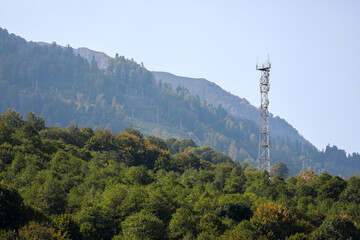 Metal structure, communication tower in a mountainous area, against the background of high mountain peaks. Russia, Krasnaya Polyana, Sochi.