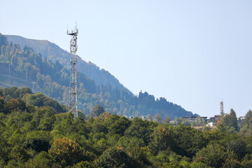 Metal structure, communication tower in a mountainous area, against the background of high mountain peaks. Russia, Krasnaya Polyana, Sochi.