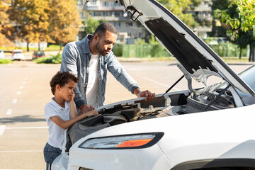 Young father teaching his son repair some parts in car