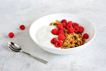 healthy breakfast with yogurt, raspberry and muesli isolated in white bowl
