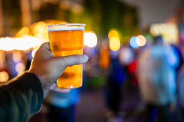 plastic cup glass with beer in hand. Outdoor summer festival