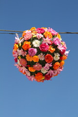 Kugel aus frischen Sommerblumen aufgehängt als Dekoration vor blauem Himmel  - 655303244
