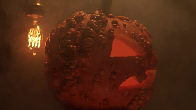 Halloween pumpkin glows with smoke, candle lights and dark night background. Dimming flickering Addison bulb. Halloween night Jack O Lantern pumpkin. Spirits and demons.