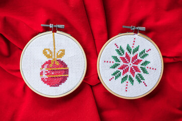 Details of handmade cross-stitch and wooden decoration for Christmas on red background. - 655313005