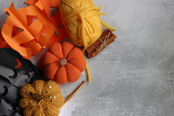 Handmade Halloween decoration on light grey background with copy space. Crocheted pumpkin, wool...