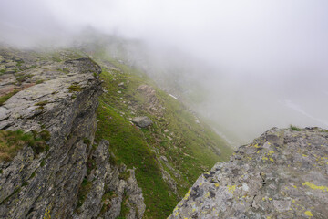 steep slopes of fagaras mountains, romania. rocks and boulders among the grass. foggy weather. mysterious adventures