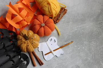 Handmade Halloween decoration on light grey background with copy space. Crocheted pumpkin, wool...