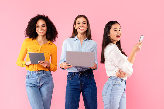 People and technology concept. Happy diverse female friends using different gadgets laptop, tablet and smartphone - Powered by Adobe