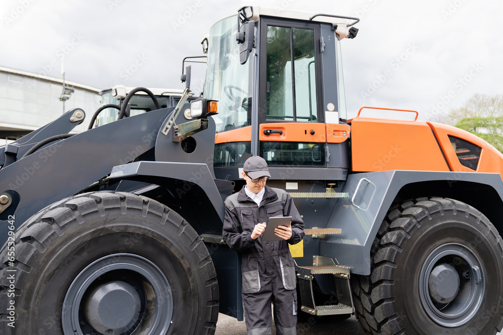 Poster Serviceman with digital tablet on a background of the tractor.