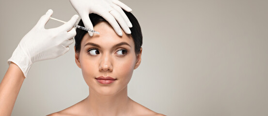 Hands of cosmetologist in gloves make rejuvenating anti wrinkle injection to calm millennial...