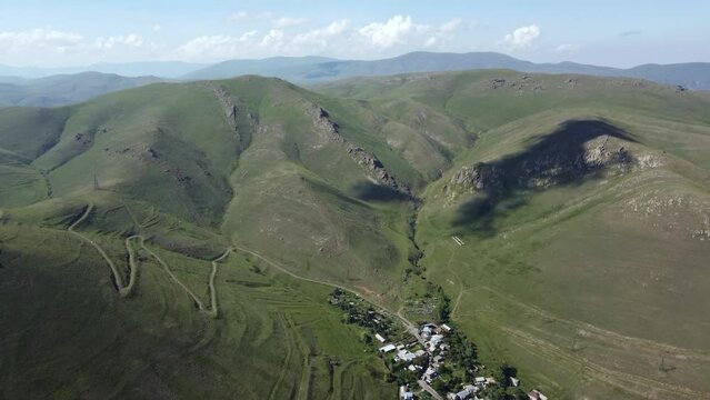 Drone footage soars above a quaint town nestled in Armenia's mountainous regions, capturing the harmonious blend of urban life and nature's grandeur.