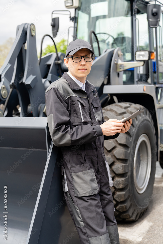 Poster serviceman with digital tablet on a background of the tractor.