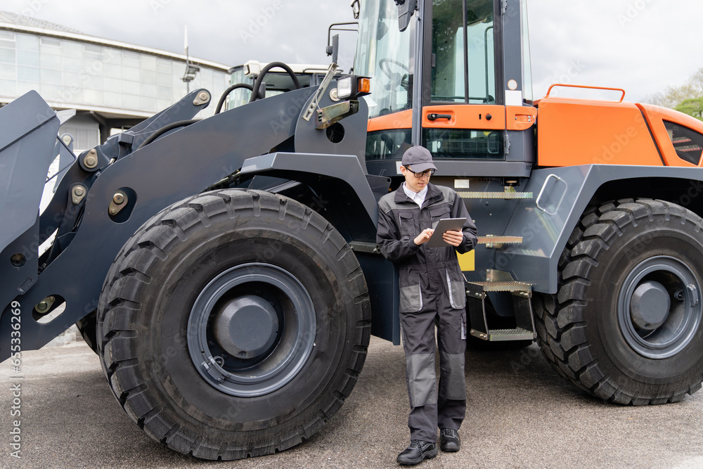 Poster serviceman with digital tablet on a background of the tractor.