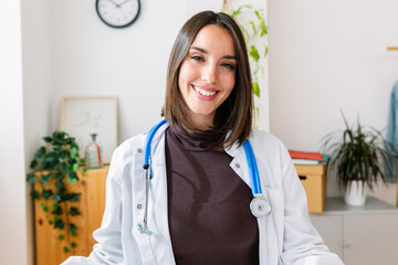 Smiling portrait of young female nutritionist doctor standing at desk office. Patient point of view of doctor online consultation. Webcam or laptop screen view