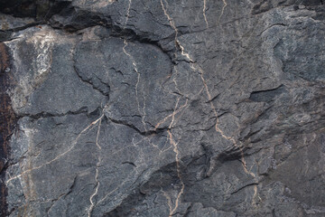 The output of dark shale rock with veins, natural stone background.
