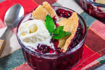 Berry cobbler in glass ramekin with ice cream, horizontal, closeup