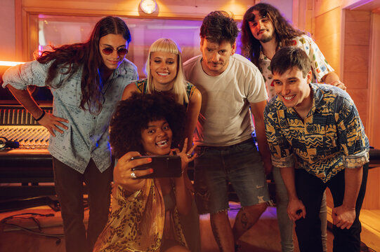 Band mates taking a photo portrait with music recording studio crew.