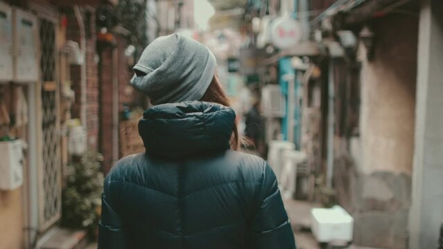 Tourist girl explore Japanese culture walking Golden Gai Tokyo streets. Woman back view enjoy backstreet alley, bars, shops. Outdoor lifestyle travel on autumn holiday vacation. Slow motion 4K