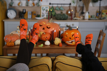 Socks. Family is celebrating Halloween together. Halloween fall party. Decor with lights, candles and pumpkins. Pumpkin jack-o'-lantern. Halloween decoration at home, indoor. Autumn Halloween decor