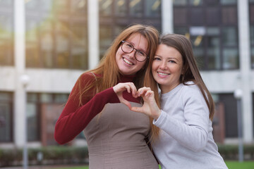 Happy two students, young lesbian LGBT women outdoors at campus. Happy homosexual female family.