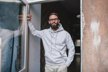 Urban Portrait of Handsome Hipster Man with a Beard Wearing a Gray Blank Hoodie with Space for your...