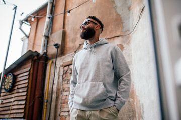 Urban Portrait of Handsome Hipster Man with a Beard Wearing a Gray Blank Hoodie with Space for your...